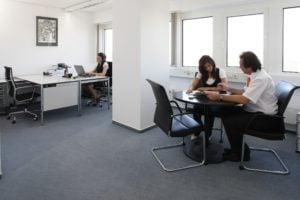 Group of People Meeting in an Office Space and People Working in the Background